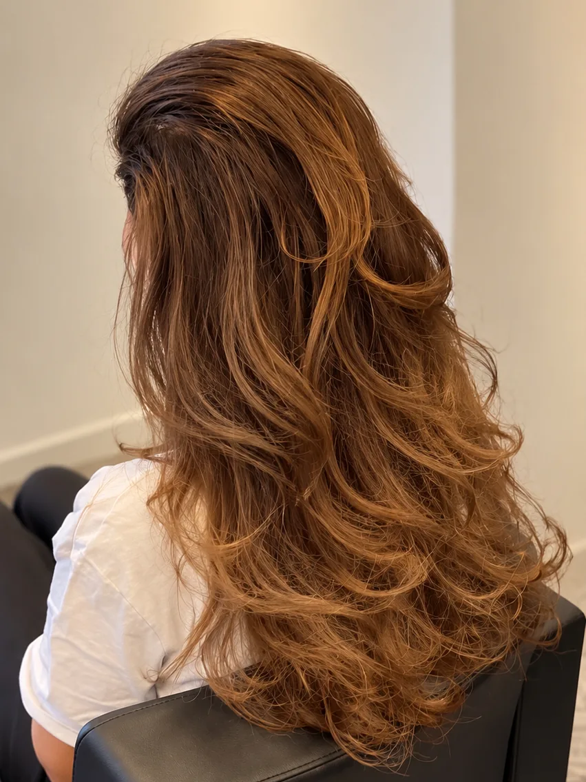 Long copper-brown hair extensions with voluminous waves, seen from behind